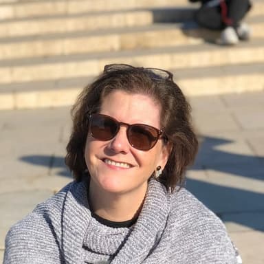 Kate Hermans, Glya’s founder, smiling on a sunlit flight of steps.